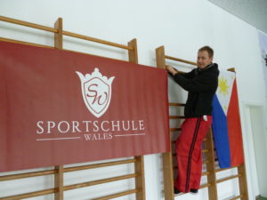 Trainer sebastian Wales hängt die Fahne der Sportschule auf
